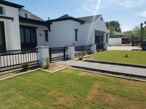 A sleek black wrought iron fence encloses a home's front patio.