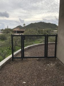 Black wrought iron gate secures a home's side yard.