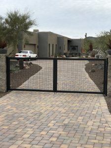 Black wrought iron gate secures a home's driveway.