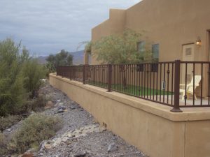 Wrought iron view fencing sits atop a home's stucco wall.