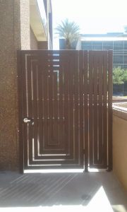 A contemporary-style wrought iron gate encloses a dumpster.