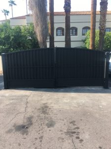 A custom wrought iron dumpster gate secures the trash enclosure on a commercial property.