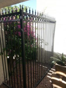 A galvanized wrought iron fence provides security for a commercial property.