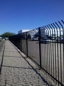 A black wrought iron fence secures a commercial property.